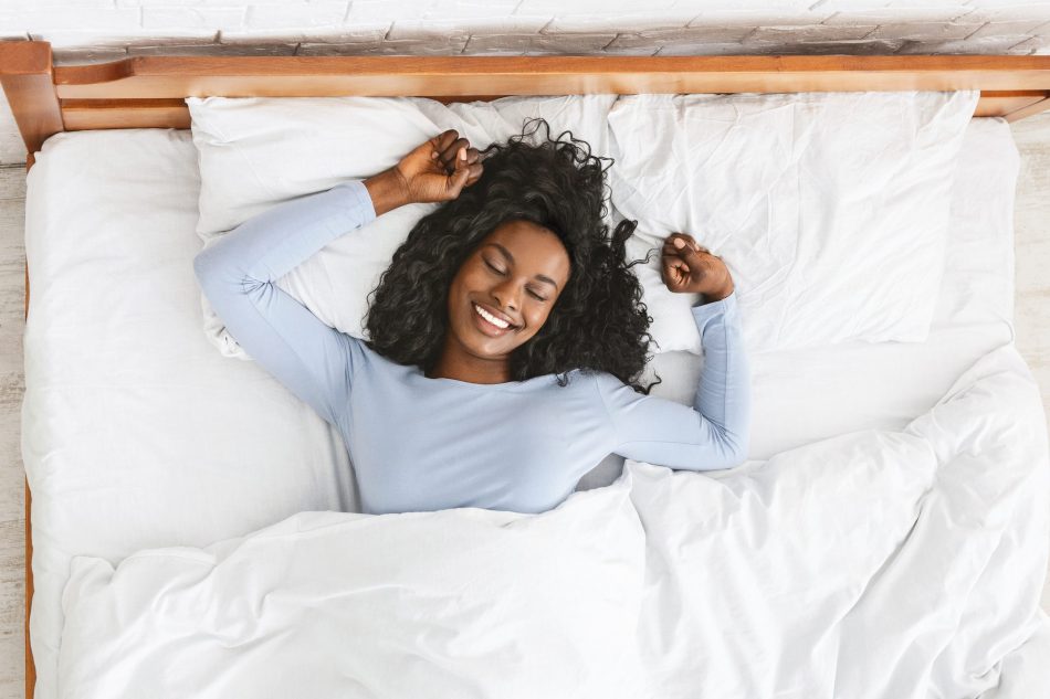 a beautiful Black woman smiles and stretches after a good rest