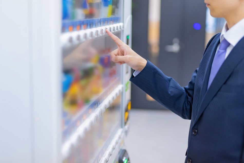 Business man presses button on vending machine