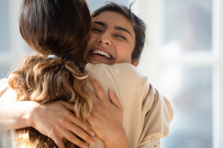 Two happy mixed-race women hugging each other