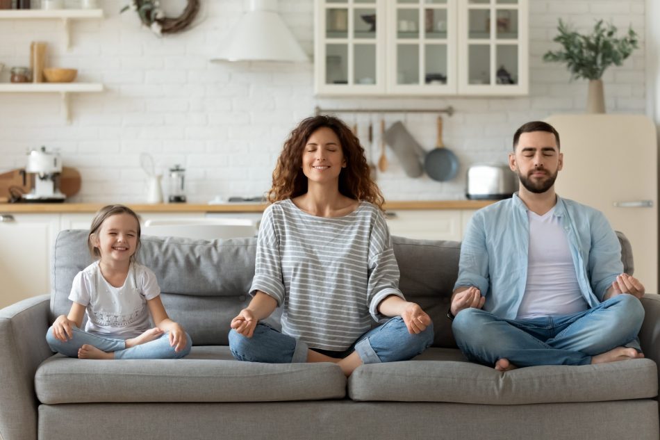 young family with child, mother, and father, all meditating on couch