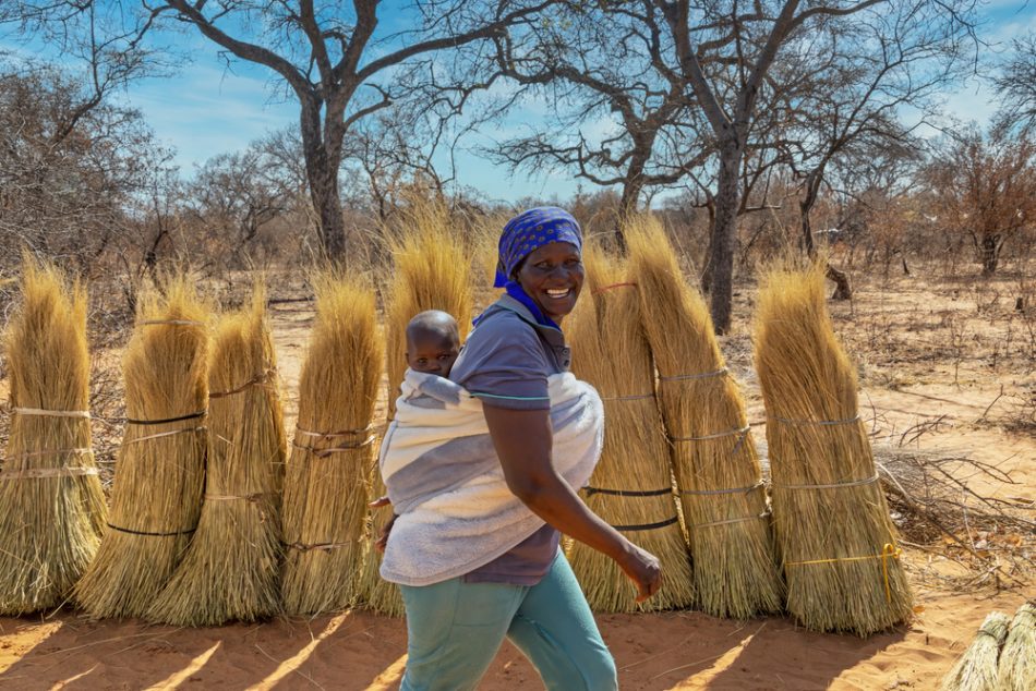 Woman walking with her child, tied to her back in a village in Botswana