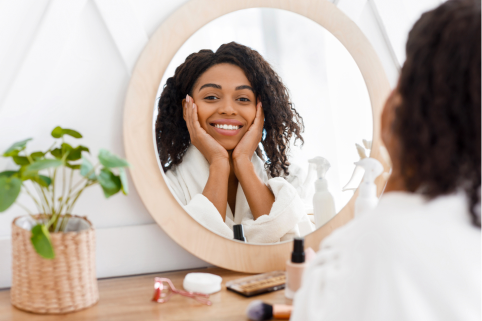 beautiful young Black woman smiles into mirror