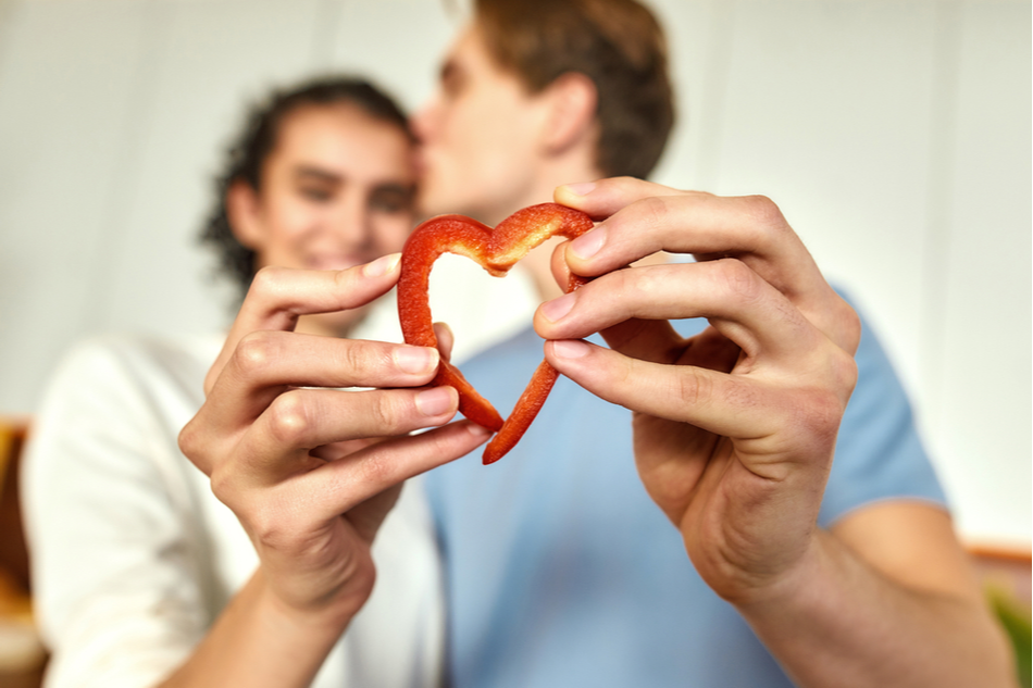 healthy vegan or vegetarian couple makes heart with two pieces of bell pepper