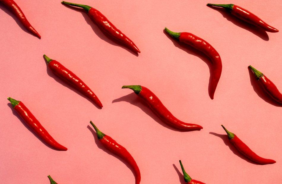 Red chilli peppers pattern on pink background.