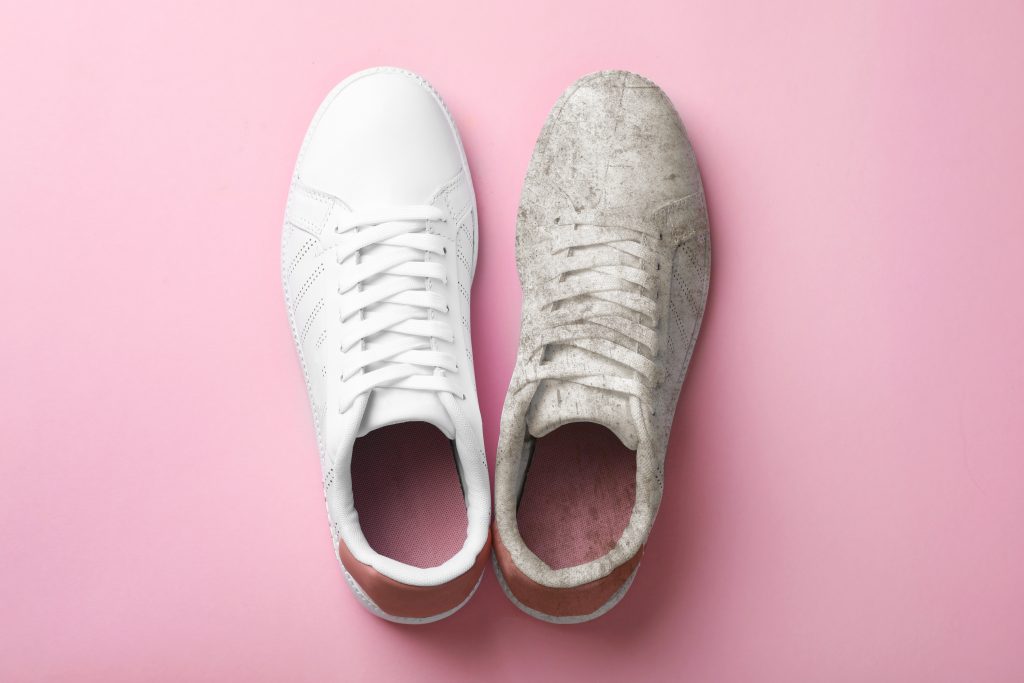 clean white shoe next to dirty white shoe against pink backdrop