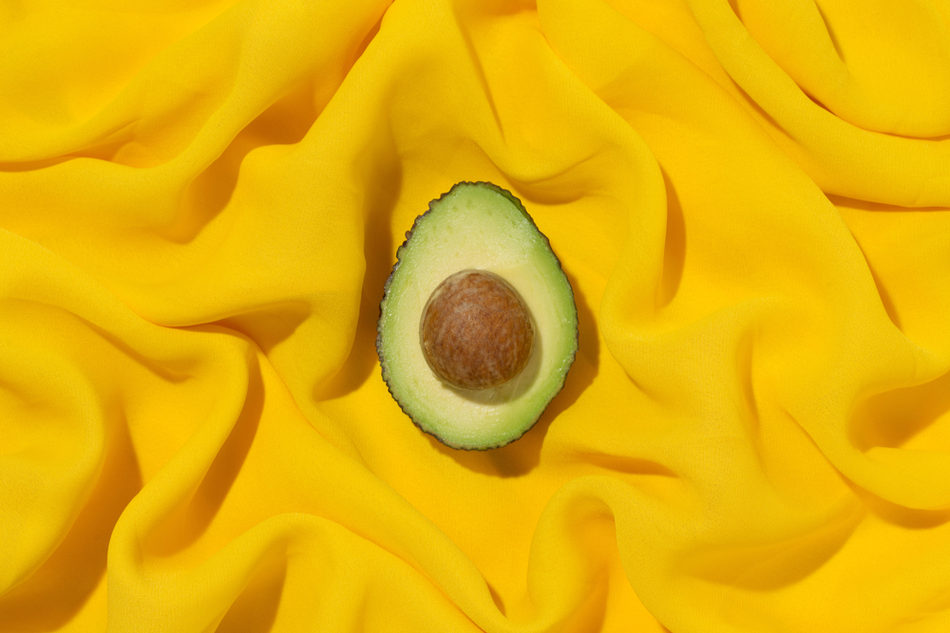 Half an avocado with seed with yellow chiffon background