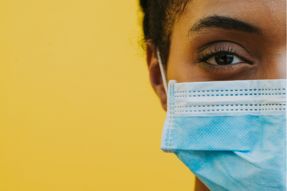 Black woman's face wearing mask against yellow backdrop