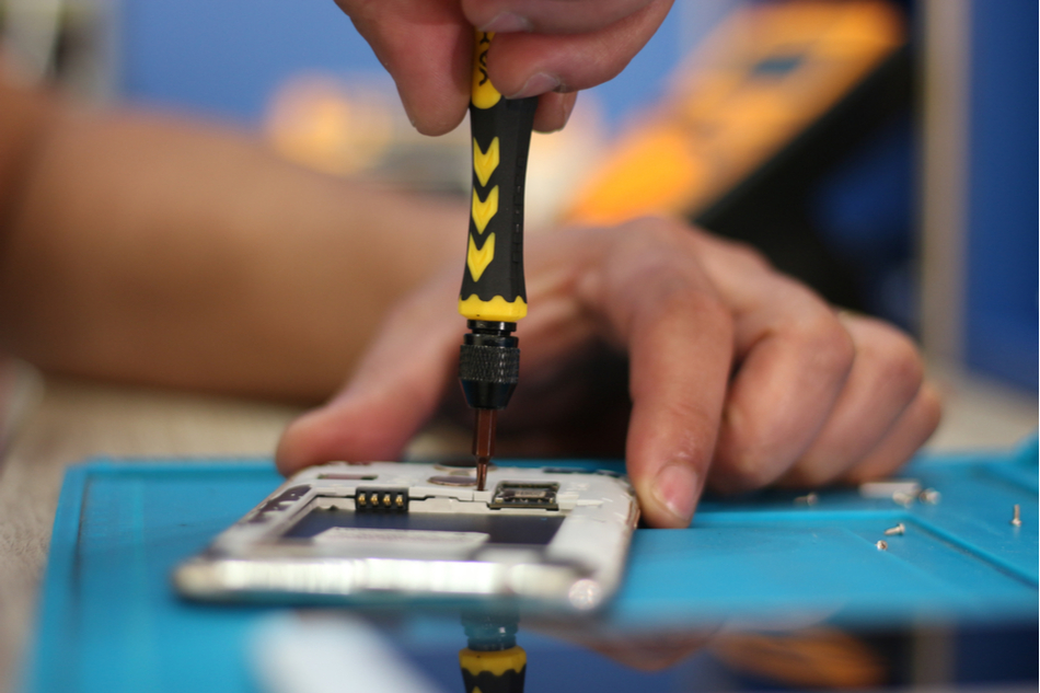 Man disassembling smartphone with a screwdriver