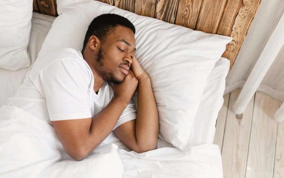 Man sleeping peacefully resting with eyes closed lying comfortable in bedroom.