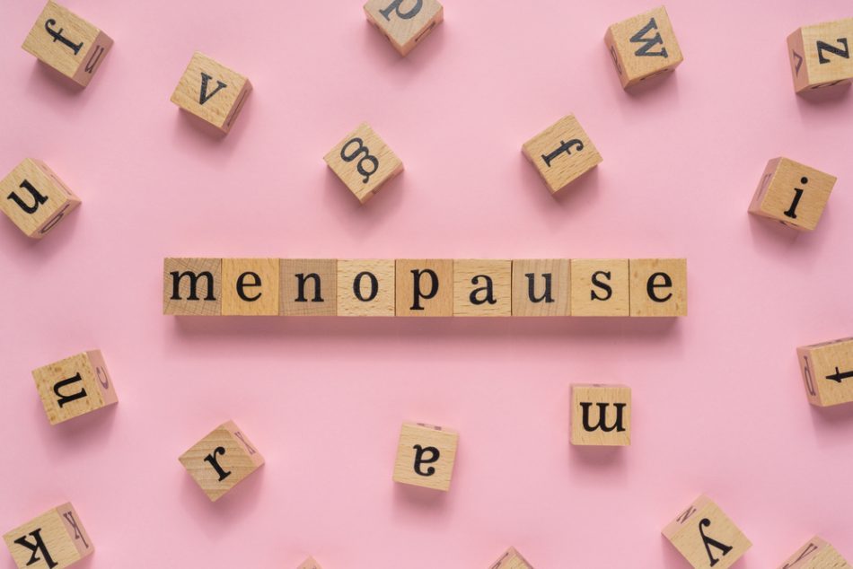Menopause word on wooden block, flat lay view on light pink background.