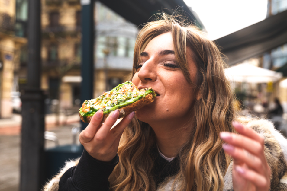 young woman happily eating avocado on toast