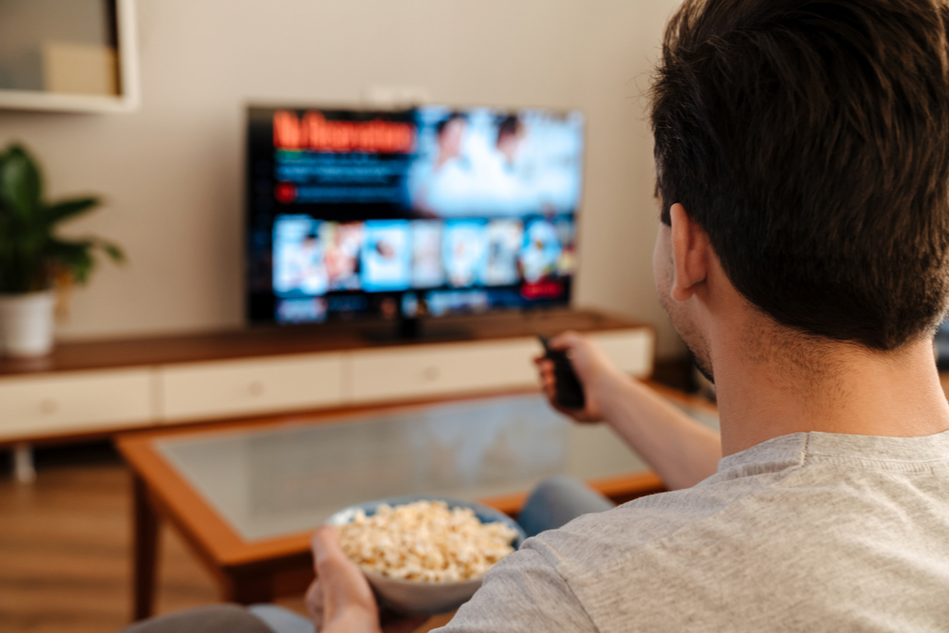man with popcorn chooses movie to watch