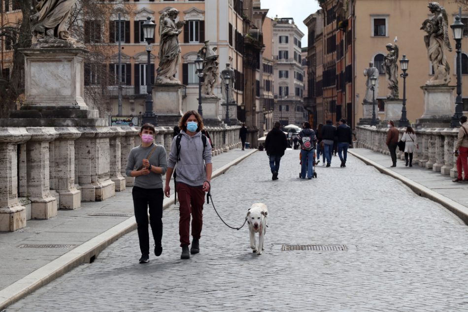 Two people walking their dog in the streets of Rome