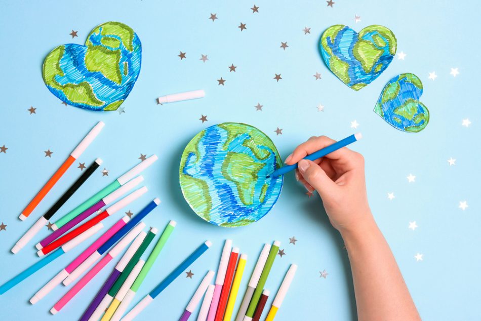 Hand draws planet Earth with multicolored felt-tip pens on on a blue background.