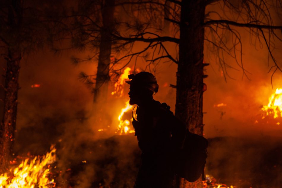 A firefighter patrols the line along a prescribed burn on the Bootleg Fire during night operations.