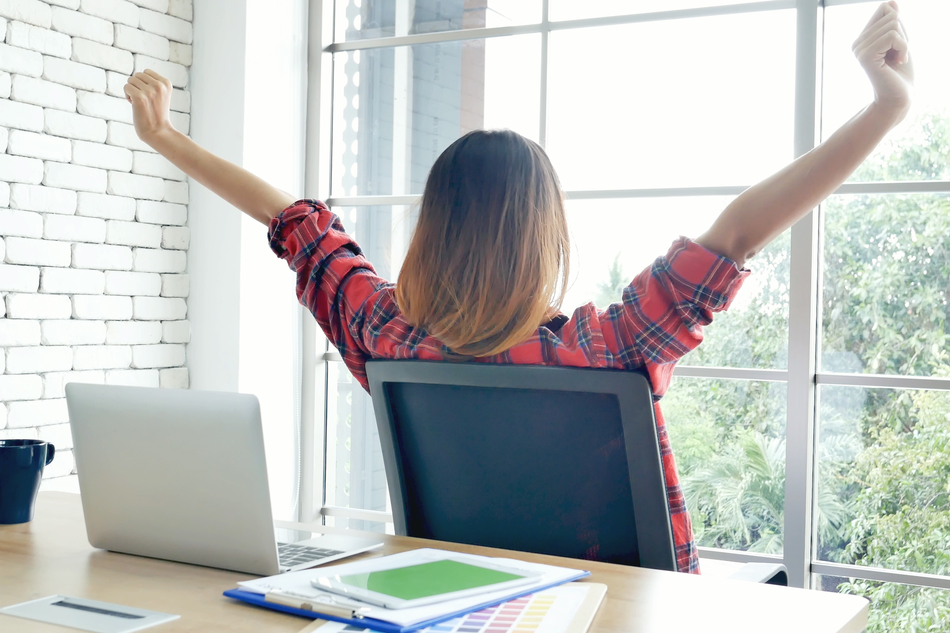 woman working from home stretches arms and looks out window