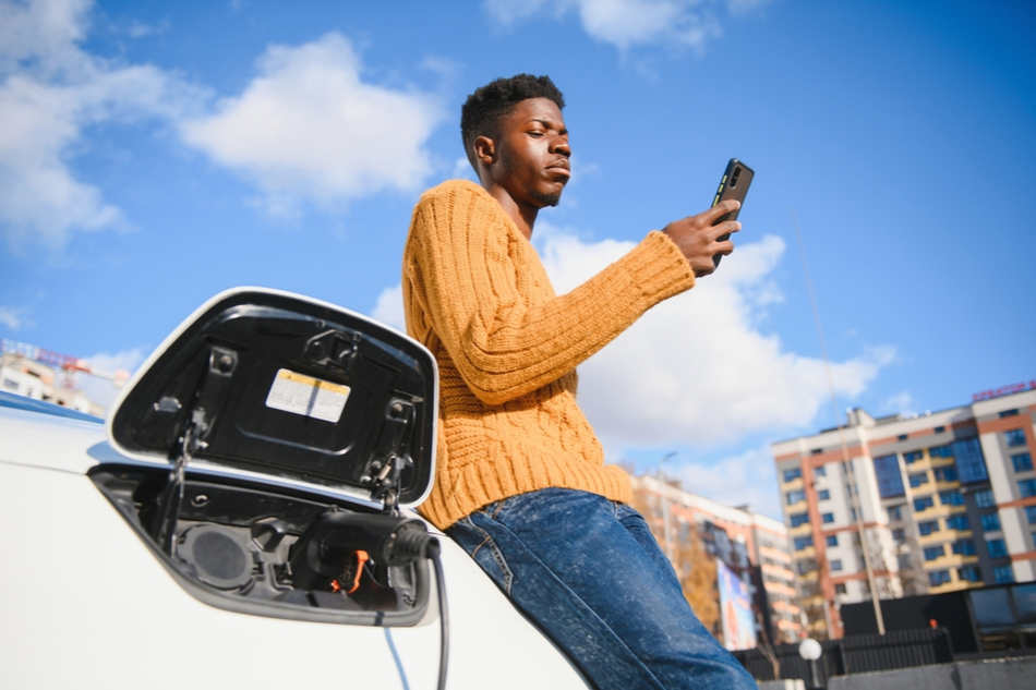 Young Black male texts while waiting for EV charge