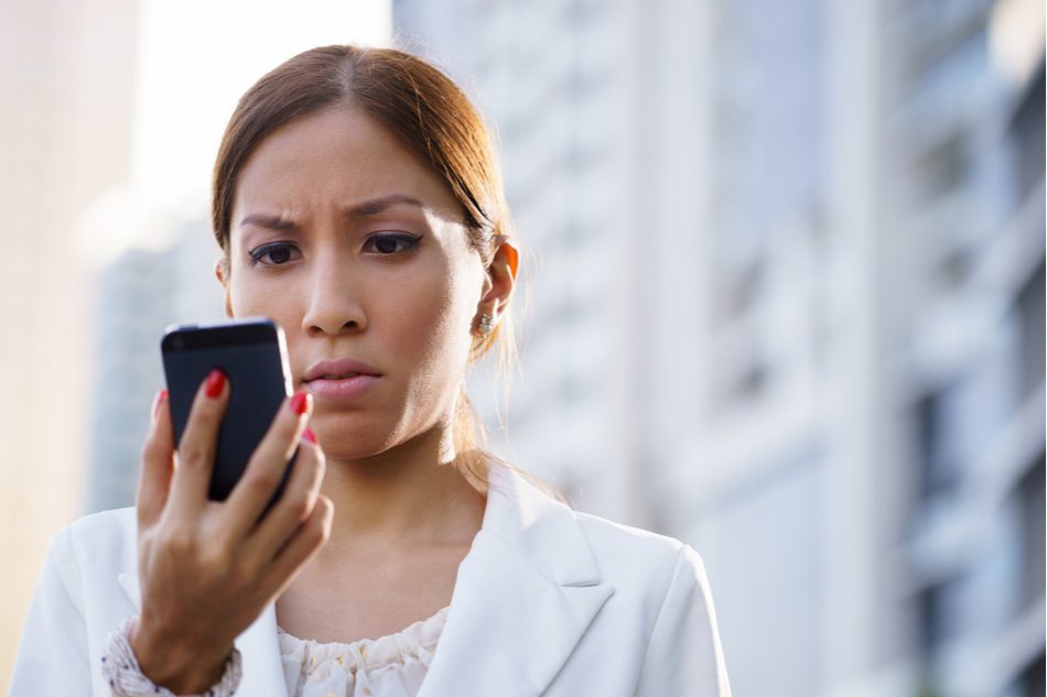 woman looks at troubling news on her phone