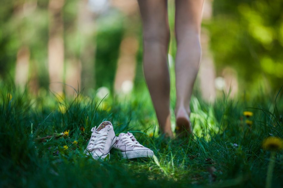 woman's legs leave shoes behind and walks barefoot in the grass