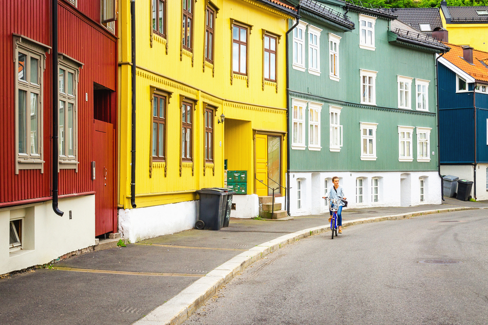 person bikes through road flanked by colorful houses in Oslo