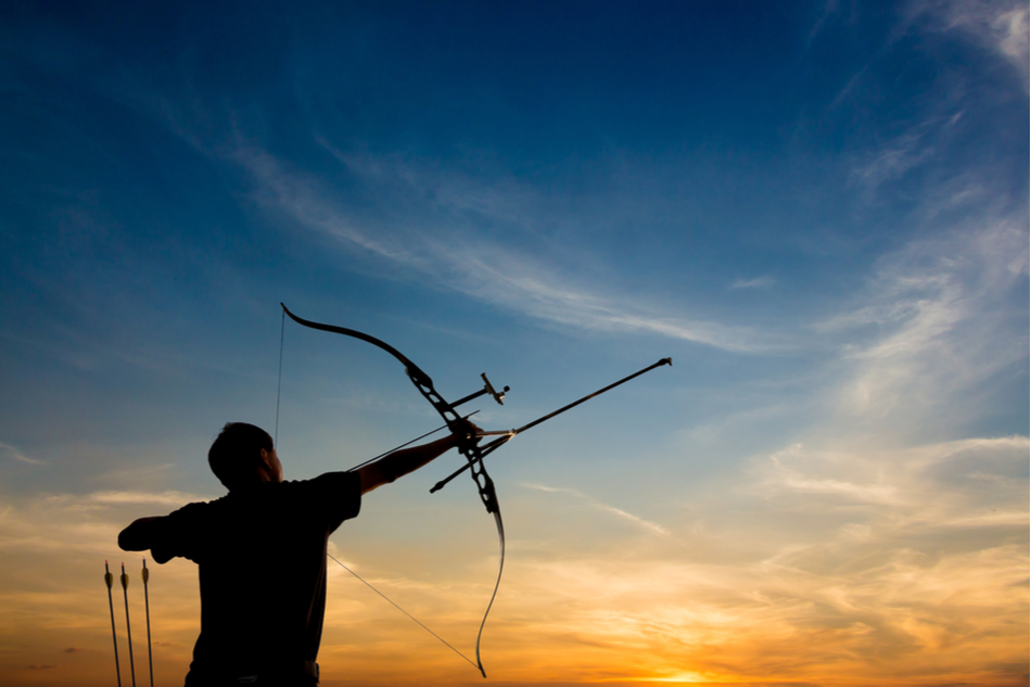 silhouette of archer shooting arrow against the backdrop of dramatic sky