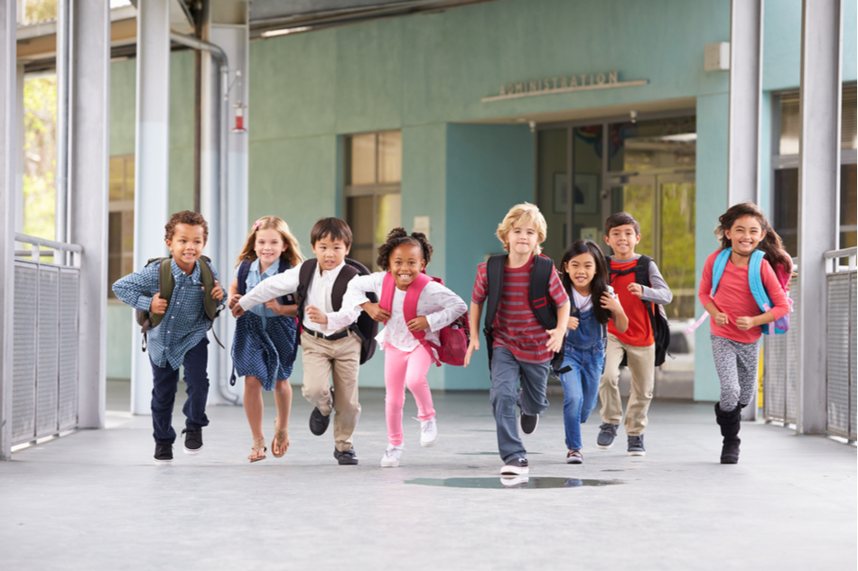 diverse group of grade school children running in a school corridor