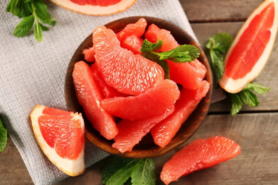 Juicy grapefruit pieces with fresh mint in a bowl, close up.