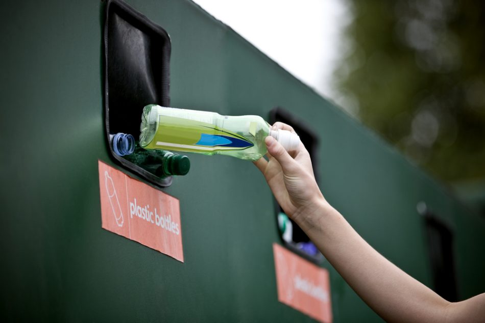 Woman recycling a plastic bottle