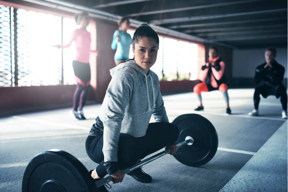 young woman lifts weight while squatting