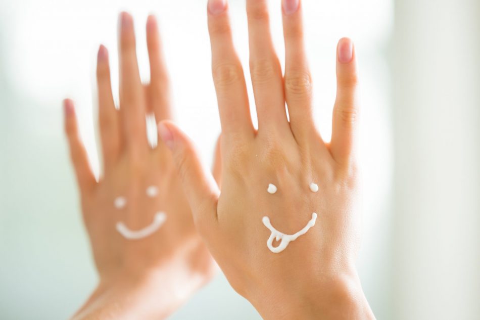 two supple hands with lotion in the form of two smiling faces