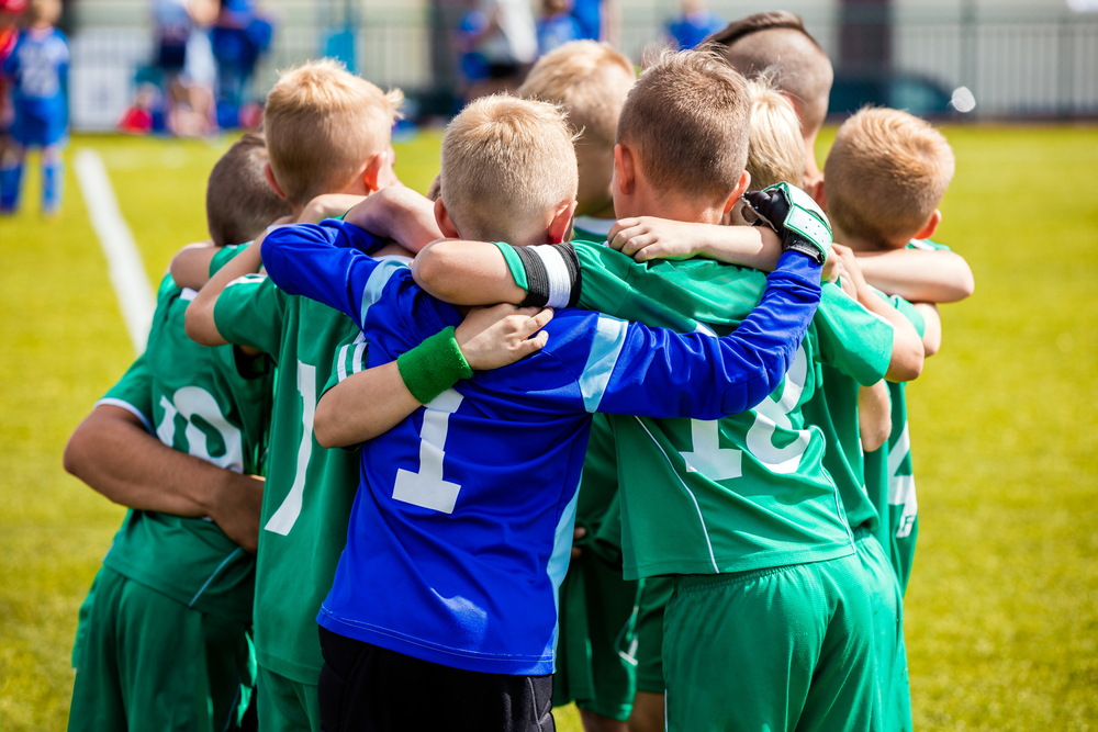 Young soccer players in blue and greensportswear, huddling round for a pep talk.