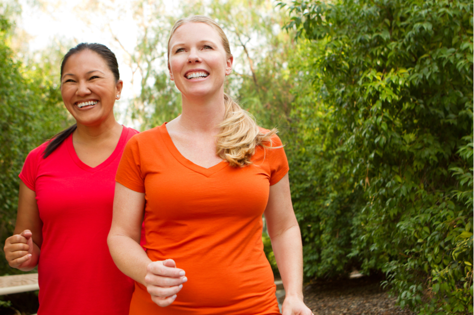 two women friends wearing vibrant t shirts walk happily in nature