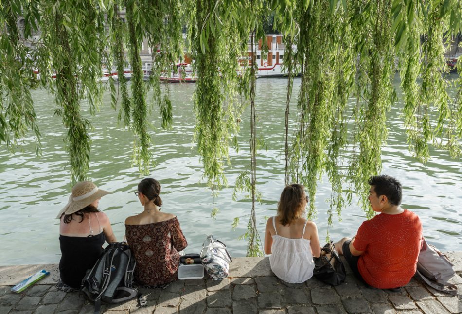 Four young people sit next to the Seine