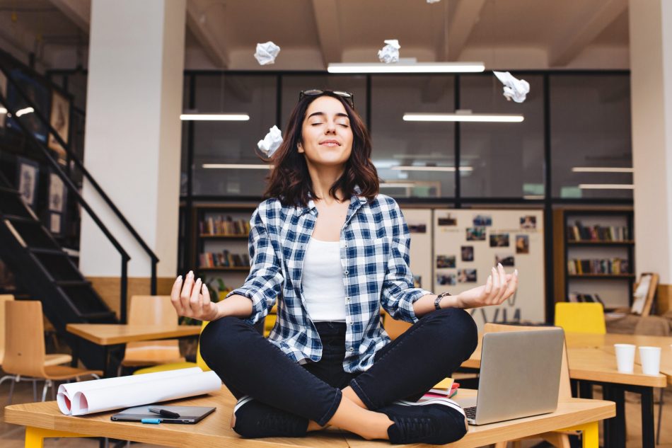 Young woman sitting in lotus position on an office desk