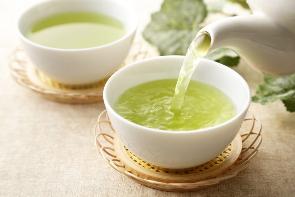 Cup of green tea being poured on a table