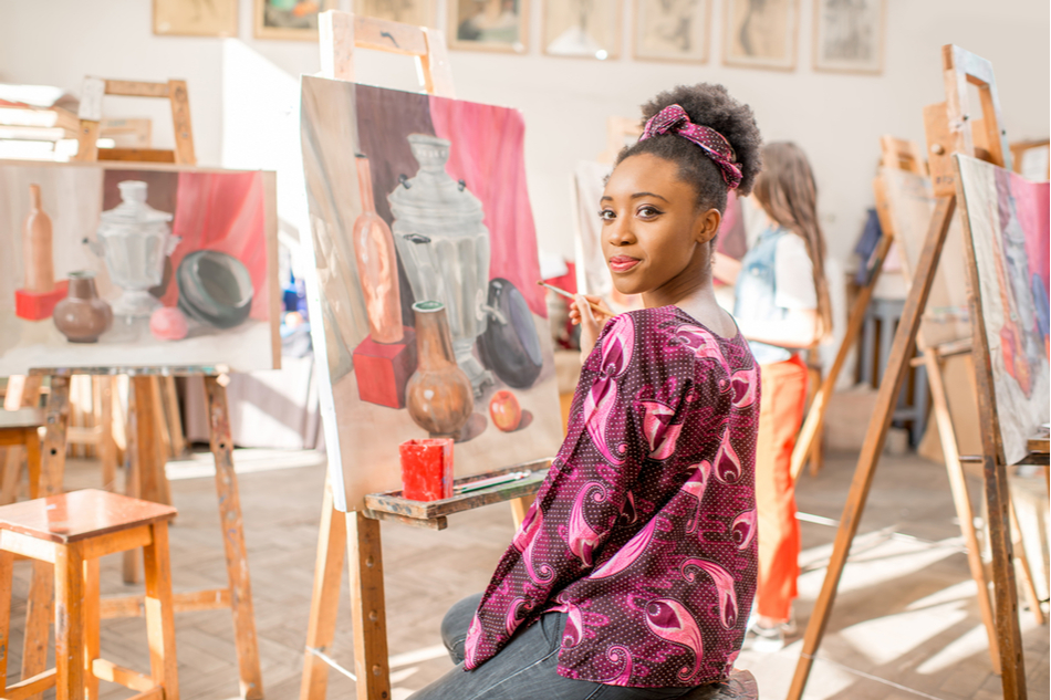 Young Black woman sitting in front of still life painting