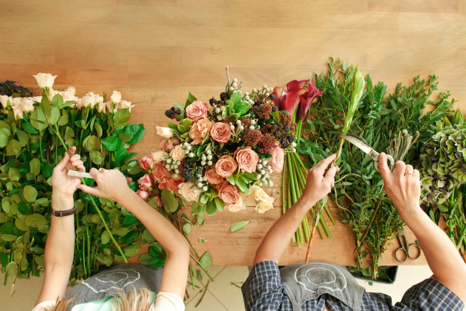 Two sets of hands cut flowers for a bouquet