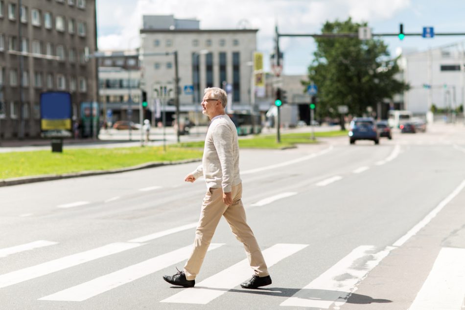 Older man walking across a crosswalk