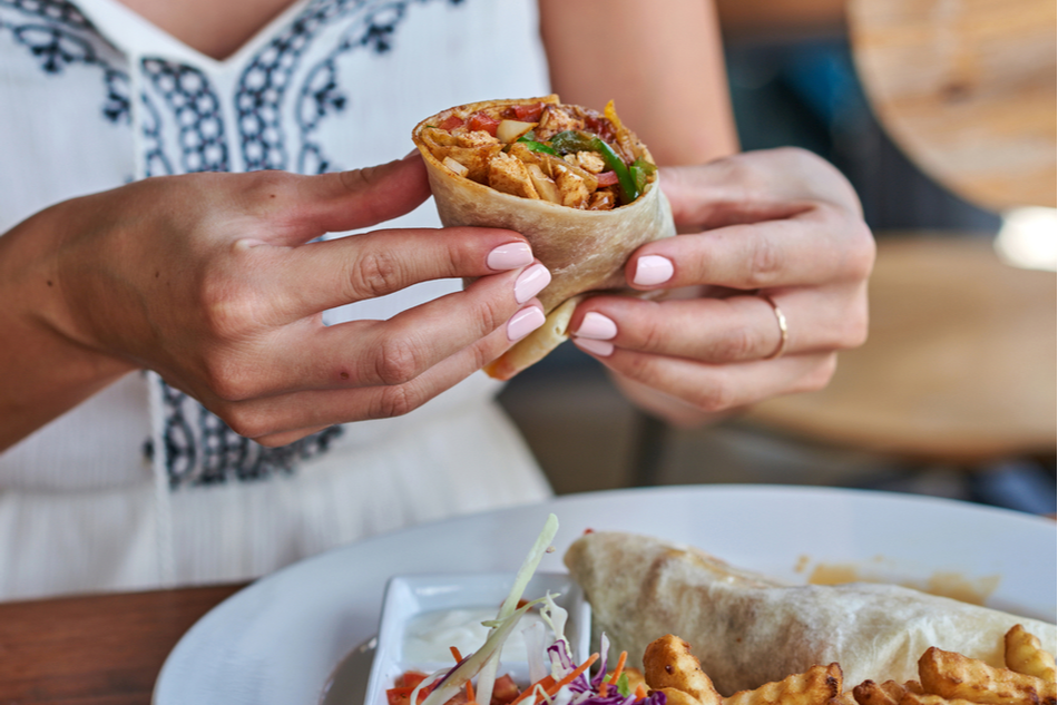 close up of woman holding burrito or wrap