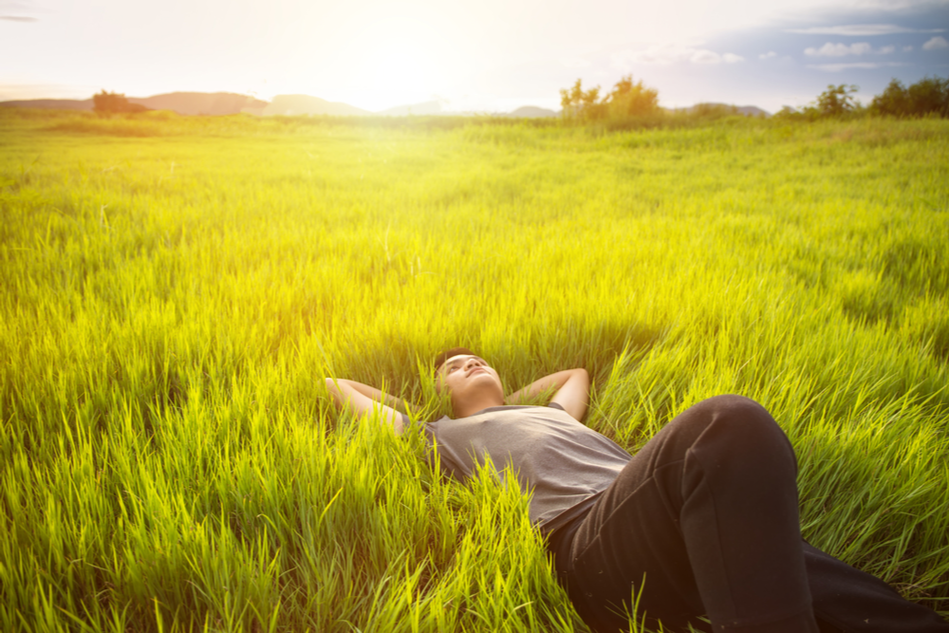 person lays blissfully in a green meadow