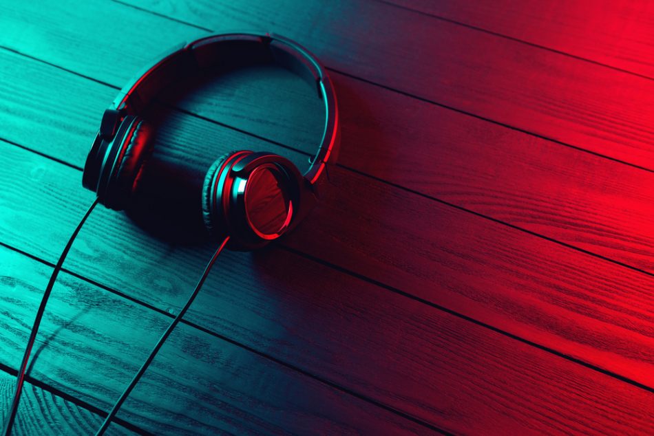 Black headphones on dark wooden background with blue and red light shining.
