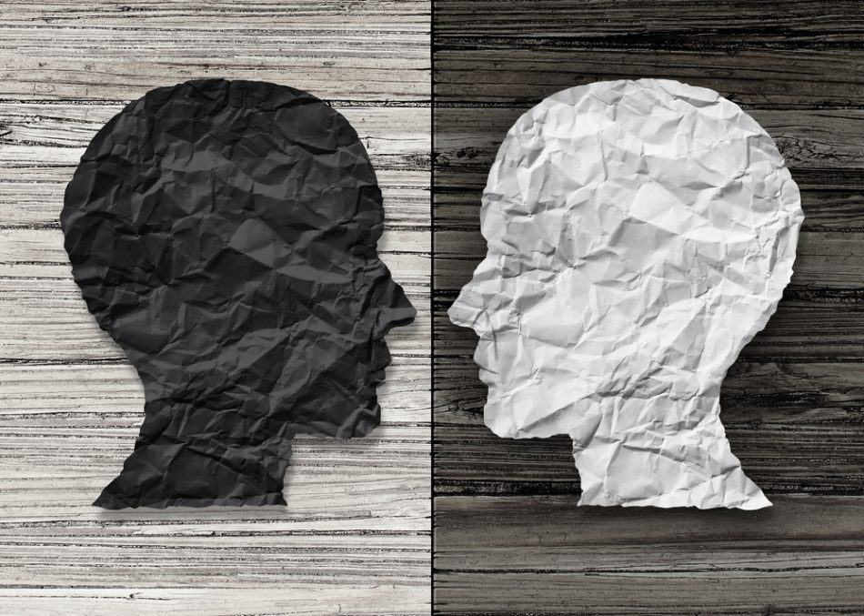 Bipolar mental health and brain disorder concept as a human head in paper divided in two colors as a neurological mood and emotion symbol or medical psychological metaphor.