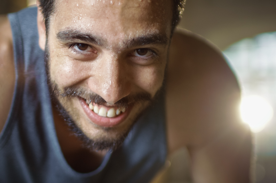 sweaty athletic man smiles directly into camera
