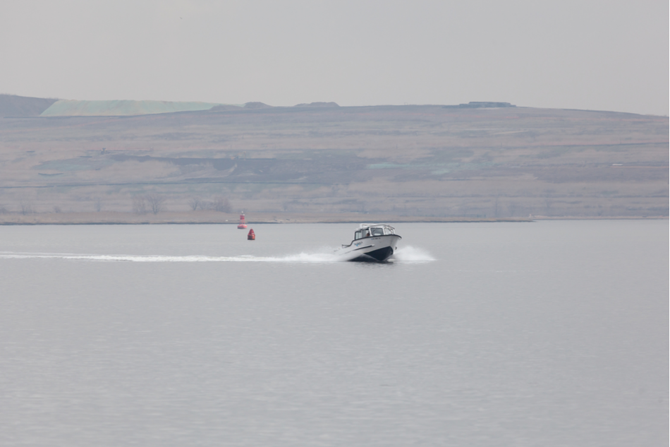 An Atlantic Response Inc. boat travels the Arthur Kill in Woodbridge on a hazy day. Fresh Kills park is seen in the background.