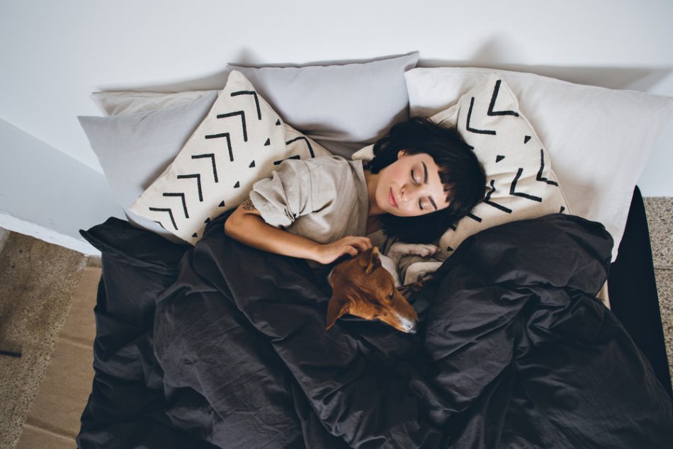 Woman sleeping with dog in bed