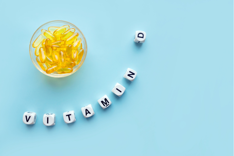 bowl of yellow vitamin D supplements with letters spelling vitamin D