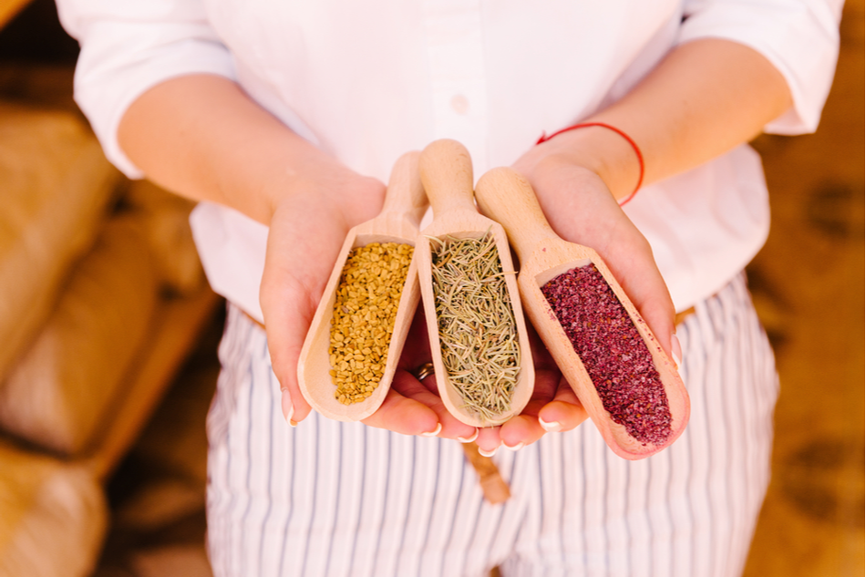 hands holding three different spices in scoopers