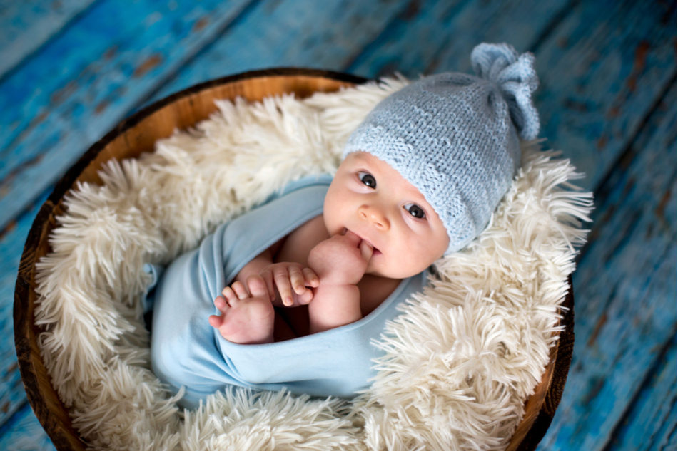 Newborn baby boy wrapped in blue looks into camera