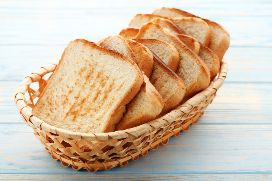Toast bread in basket on blue wooden table.
