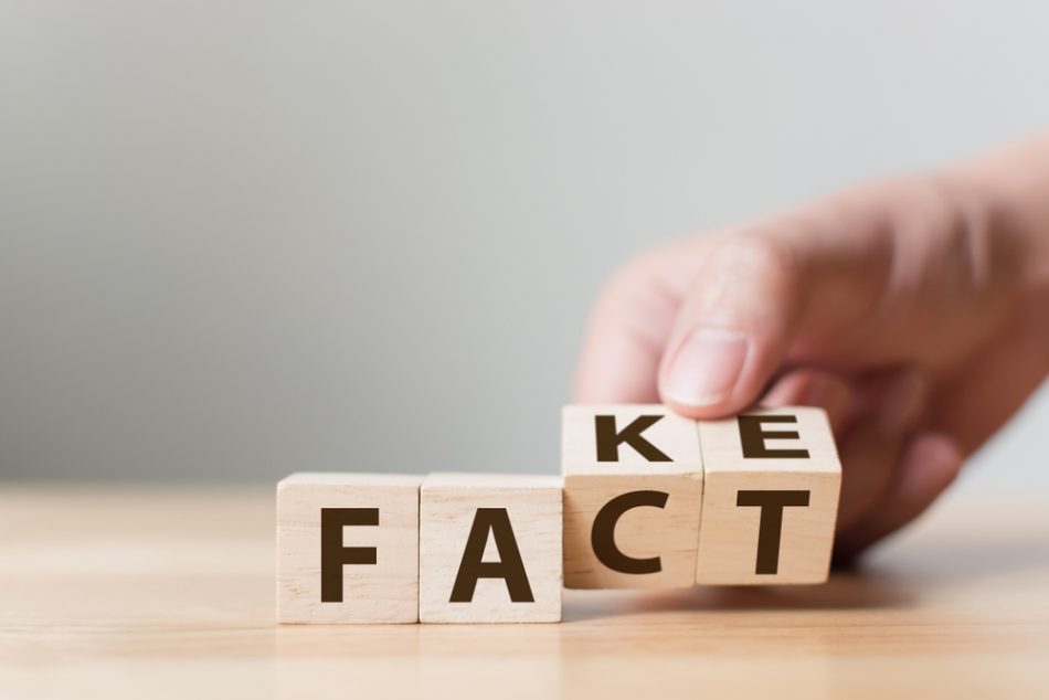 Fact or fake concept, hand flippimg wood cube to change the word.